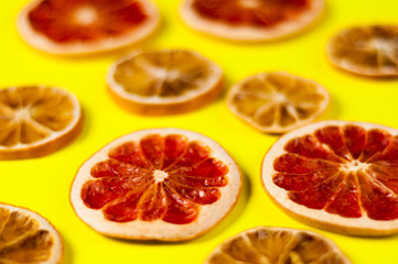 Scattered dried slices grapefruit and lemon on yellow background