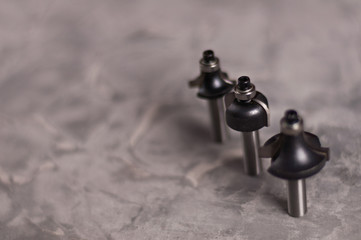 Row of three steel router bits for milling cutter on old broken worn gray concrete floor with copy...