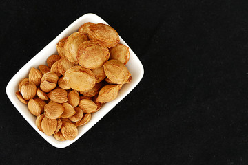eat apricot kernels, fruit kernels,
eat apricot kernels in plates, on black ground, Sweet apricot seeds,


