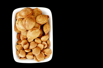 eat apricot kernels, fruit kernels,
eat apricot kernels in plates, on black ground, Sweet apricot seeds,



