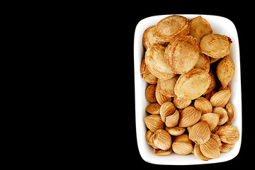 eat apricot kernels, fruit kernels,
eat apricot kernels in plates, on black ground, Sweet apricot seeds,


