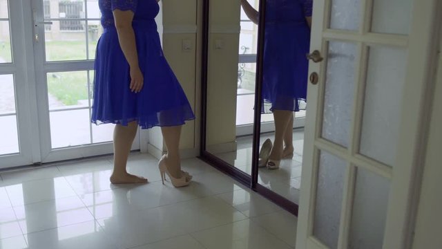 Fat girl in a blue dress in front of a mirror