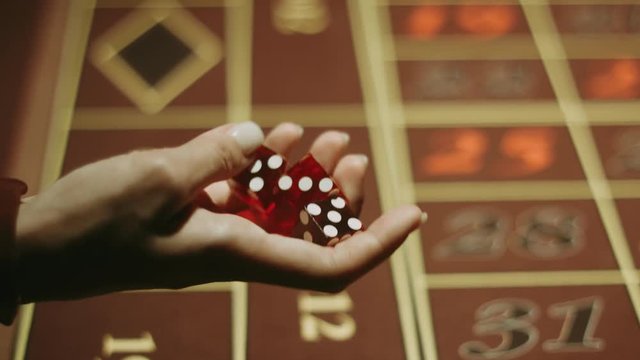 Player with red dices near gambling table. Close up woman hand holding three dices. Game of chance in casino. People playing in craps game. Gambling addiction problem