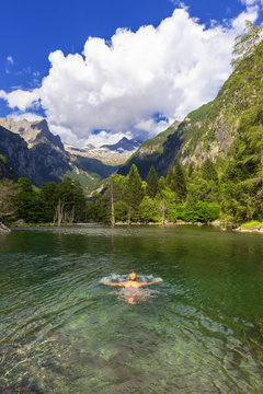 A girl swims in a clear alpine lake, Val di Mello (Mello Valley), Valmasino, Valtellina, Lombardy