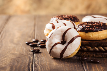 Glazed mini gluten free donuts with coffee candies on wooden background. Party food concept with copy space.