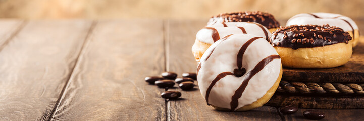 Glazed mini donuts with coffee candies on wooden background. Party food concept with copy space....