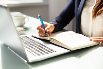 Close-up Of A Businesswoman's Hand Writing Note In Diary
