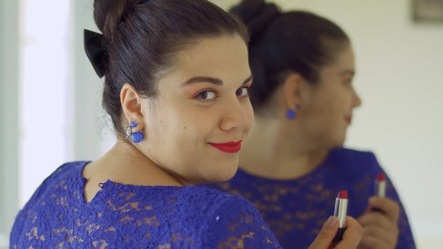 Fat girl paints her lips in front of a mirror