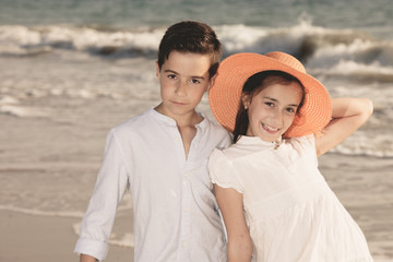 Obraz premium boy and girl on the beach, she with an orange hat