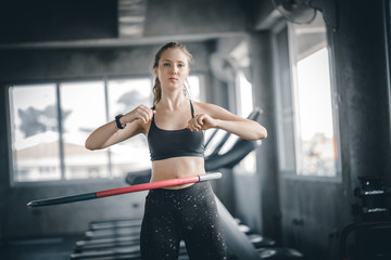 Obraz na płótnie Canvas Beautiful caucasian young woman doing hula hoop in step waist hooping forward stance. Young woman doing hula hoop during an exercise class in a gym. Healthy sports lifestyle, Fitness, Healthy concept.