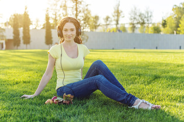 Fototapeta premium Beautiful modern girl listening to music with her headphones in autumn Sunny Park. Favorite music, happy time.