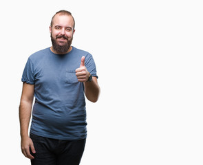 Young caucasian hipster man over isolated background doing happy thumbs up gesture with hand. Approving expression looking at the camera with showing success.