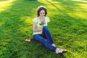 Modern woman with dreadlocks listening to music with her headphones in autumn Sunny Park