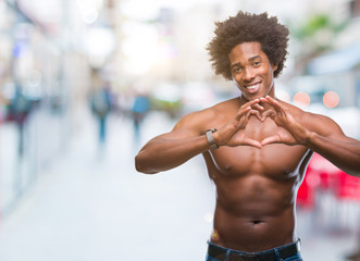 Fototapeta na wymiar Afro american shirtless man showing nude body over isolated background smiling in love showing heart symbol and shape with hands. Romantic concept.