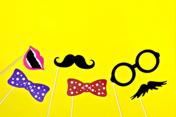 Moustache, tie, glasses, red mouth on wooden sticks against a bright yellow background Month donations concept for the study and control of prostate cancer and other male diseases Mock up Flat lay 