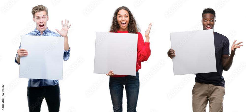 Wall mural Composition of young people holding blank banner over isolated background very happy and excited, winner expression celebrating victory screaming with big smile and raised hands