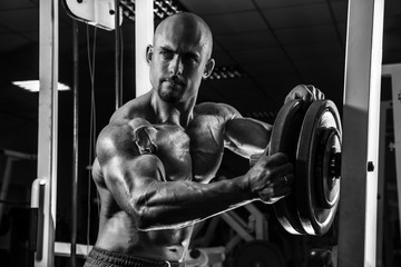 Fototapeta na wymiar White Muscular man is posing in the gym with weight plate BW