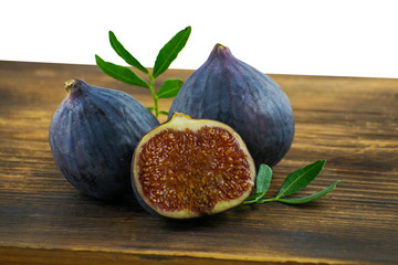 Tasty figs on wooden board. Photo of figs with slice and leaves on wooden board. Autumn season food photo.