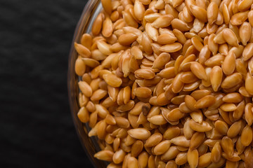 seeds of golden flax on a dark stone background
