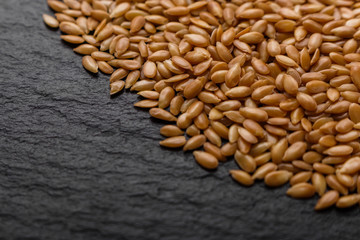 seeds of golden flax on a dark stone background