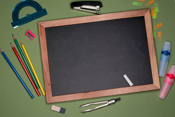 School concept. Empty chalk board, stationery on green background, copy space.