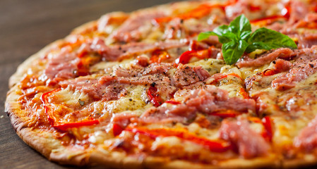 slices of Pizza with Mozzarella cheese, ham, pepper, meat, Tomatoes, Spices and Fresh Basil. Italian pizza on wooden background