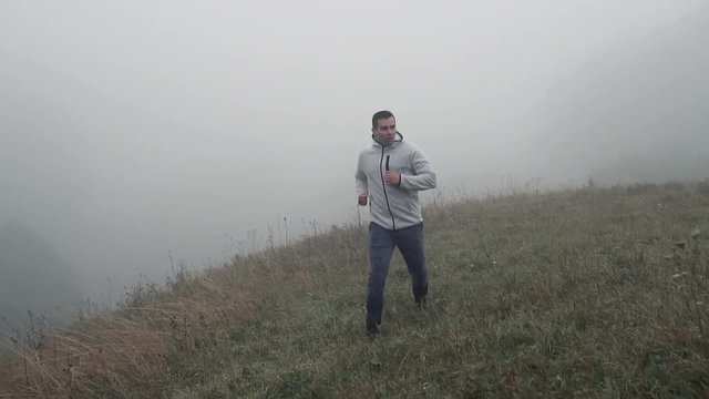 Jogging man athlete on the grass in the fog,slow mo
