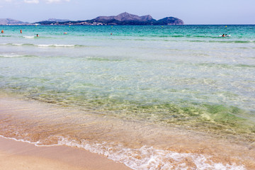 Summer beach with emerald crystal clear water and sand cakes left on the white sand beach. Playa de Muro, Mallorca, Balearic islands, Spain.
