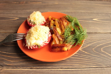 Tomatoes with cheese and fried potatoes on an orange plate.