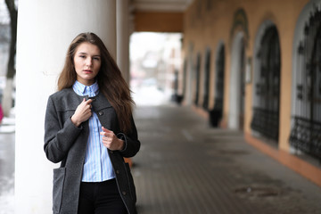 Fototapeta premium Young beautiful girl on a walk near building with a column