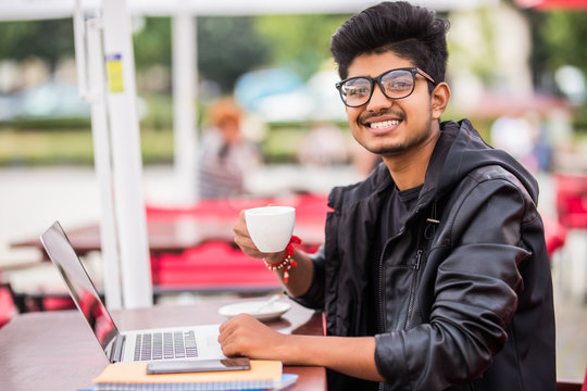 Young Asian indian man sitting in coffeeshop table and working on laptop