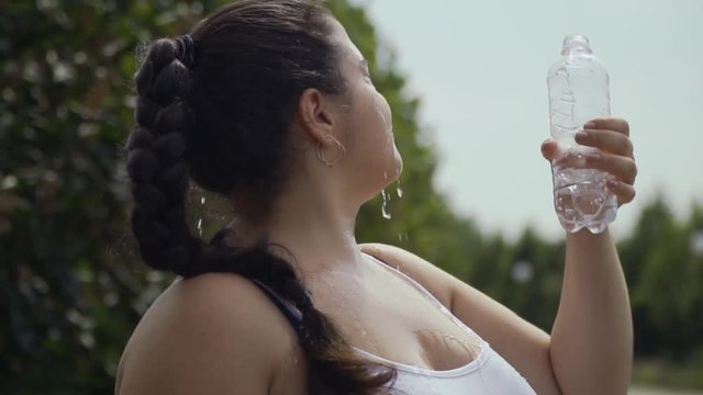 Fat girl pours water on herself from a bottle