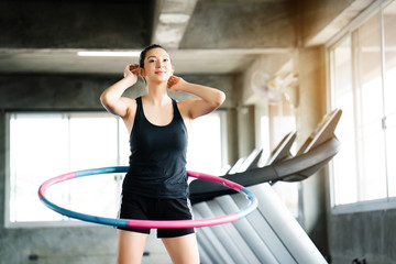 Beautiful Asian women wearing sportswear. Playing hula hoop in the morning gym. Helps to burn excess fat in the body. Strengthens the muscles of the body. Increases blood flow to the brain.