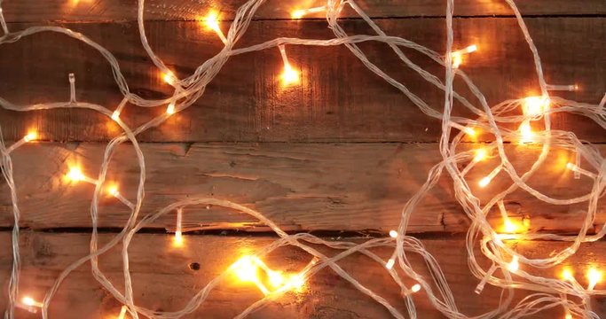 Flat lay glowing Christmas lights with copy space on wooden plank background. Shot in 4k resolution