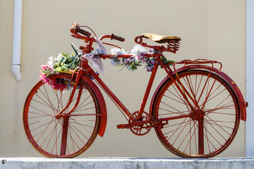 Old Bicycle decorated with flowers against the wall isolated.