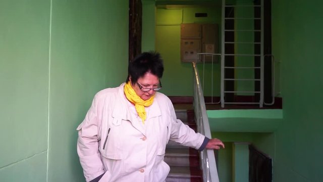 an elderly woman comes down the stairs in the entrance MLS 1