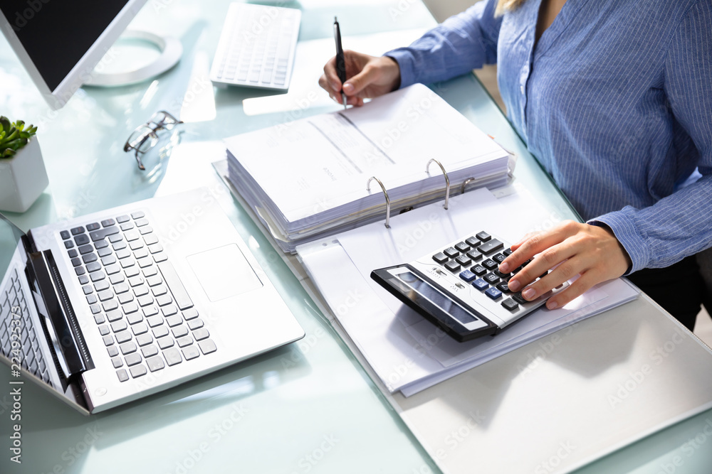 Poster businesswoman's hand calculating bill in office