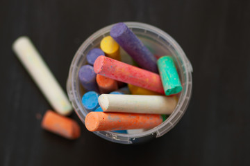 Color chalk in plastic cans closeup on blackboard. Selective focus