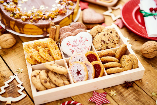 old wooden table with delicious Christmas cookies in a box and various decorations