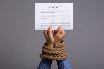 Woman's Hand Tied With Rope Holding Contract Form