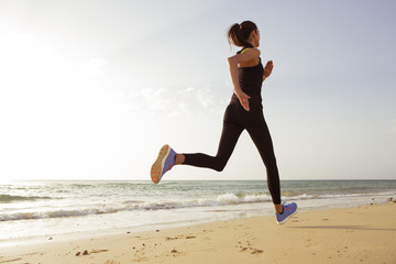 Young sport woman running in the morning on the beach.