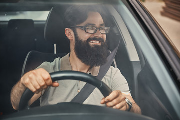 A modern bearded man driving a car