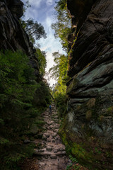 Wanderin mit Rucksack läuft einen steinigen Weg zwischen zwei Bergen hinauf 