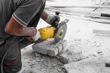 Worker cutting limestone block with power tool saw