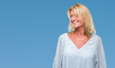 Middle age blonde business woman over isolated background looking away to side with smile on face,...