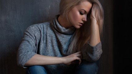 Obraz premium Depressed woman. blonde girl sitting on the floor, sadness and depression
