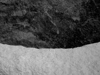 The Curvature of a Rock, Showing Small Dimples and Indents on the Top of the Outline, Against a Blurred Stone Background.