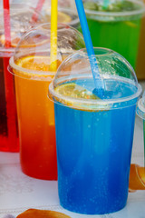 Colorful cold toning cocktails in plastic cups with cocktail straws
