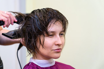 Beautiful young woman in hairstyle salon getting bob haircut