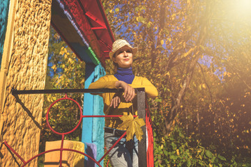 Obraz na płótnie Canvas beautiful woman in blue poloneck and yellow cardigan and hat is holding yellow maple leaf